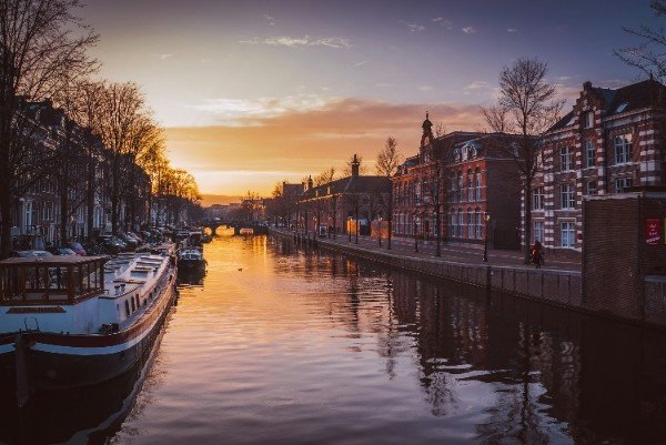 Romantic canal boat cruising at sunset in Amsterdam with golden water reflections Amsterdam Canal Boat Ride – Golden Sunset Reflections